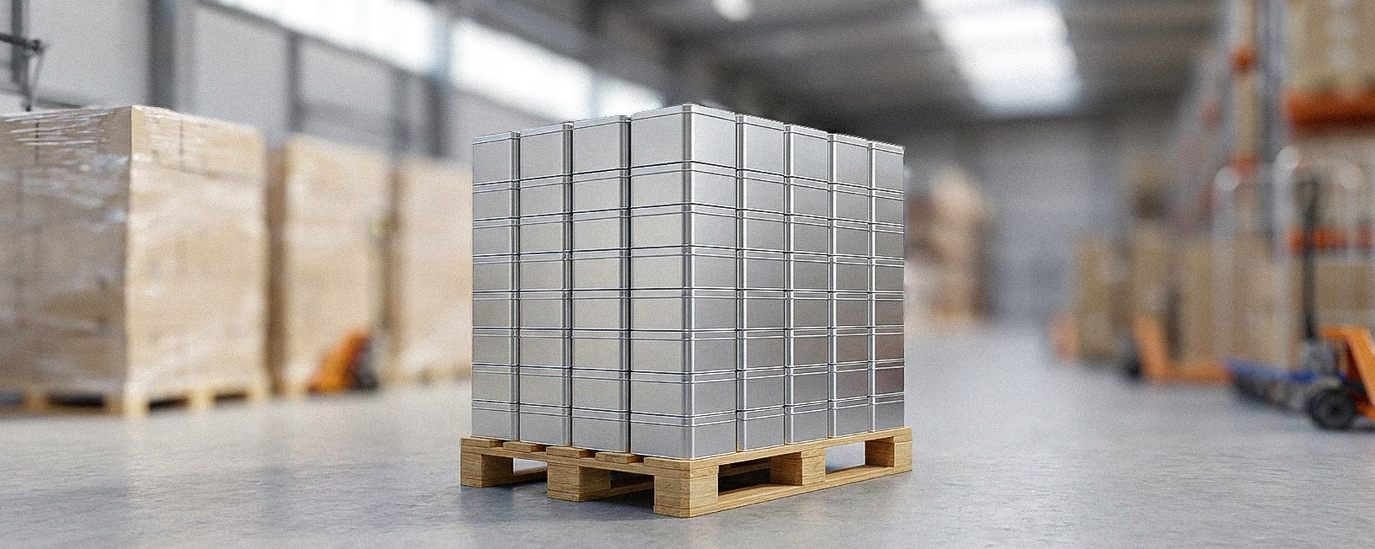 Lagerhalle mit Paletten, gestapelten silbernen Metallboxen und Logistikgeräten zwischen Regalen mit Kartonware.