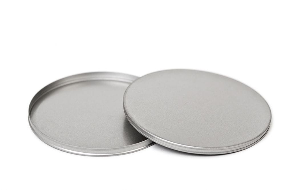 Geöffnete runde Blechdose mit abgenommenem Stülpdeckel, silberfarben, neutraler Hintergrund.
