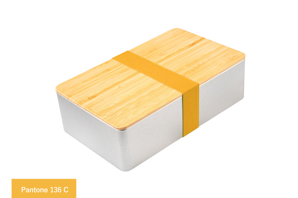 Eckige Blechdose aus silberfarbenem Metall mit Bambusdeckel, versehen mit gelbem Farbband (Pantone 136 C), auf weißem Hintergrund.