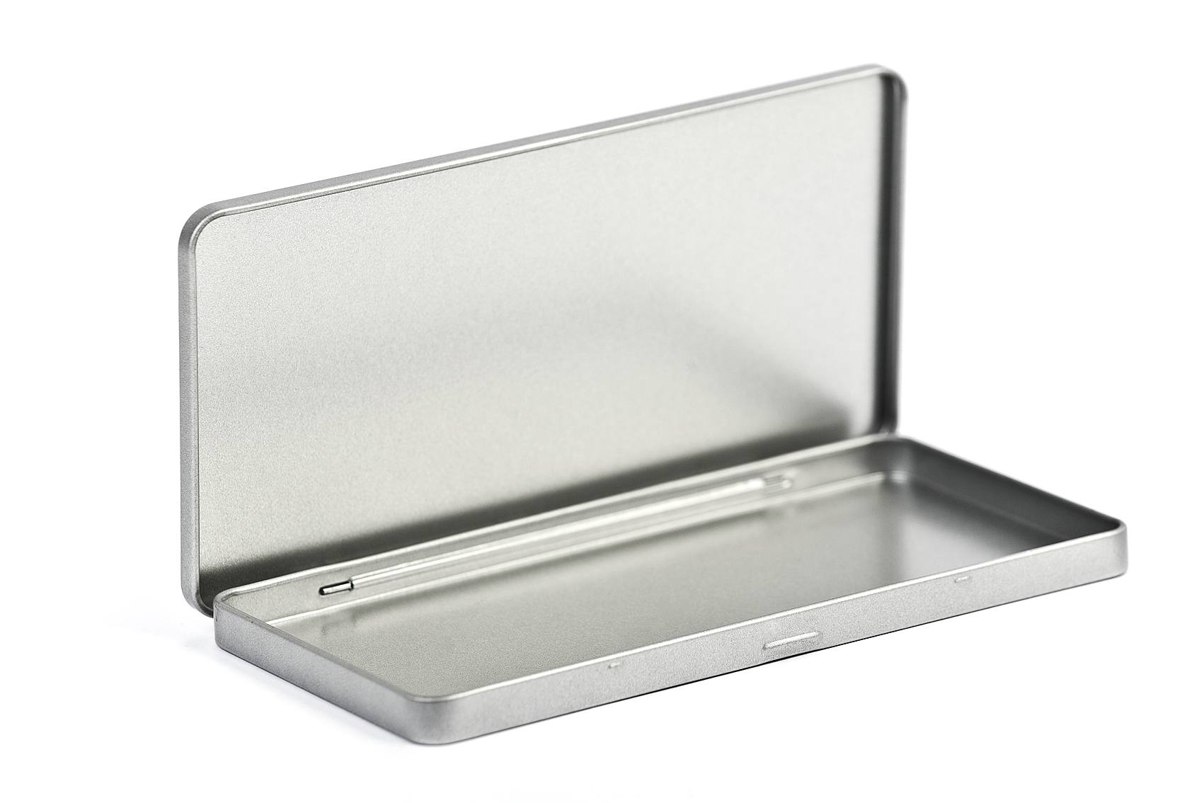 Geöffnete eckige Blechdose aus silberfarbenem Metall mit Scharnierdeckel, auf weißem Hintergrund. Der Deckel ist vollständig geöffnet und zeigt den Innenraum der Dose.