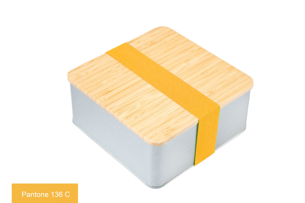 Eckige Blechdose aus silberfarbenem Metall mit Bambusdeckel, versehen mit gelbem Farbband (Pantone 136 C), auf weißem Hintergrund.