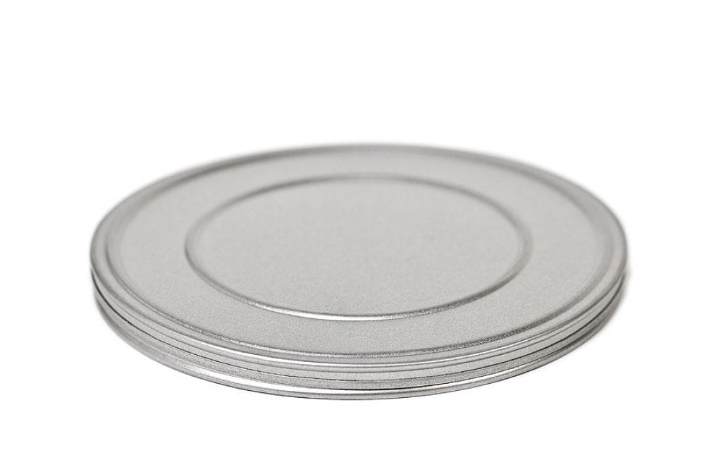 Geschlossene runde Metalldose aus silberfarbenem Blech mit flachem Stülpdeckel, auf weißem Hintergrund fotografiert.